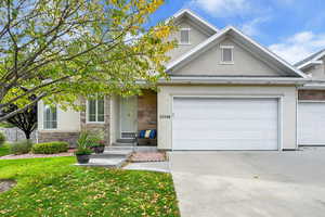 View of front facade featuring stone siding, stucco siding, and concrete driveway