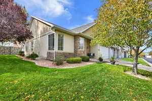 View of front facade with stone siding, stucco siding, concrete driveway, and roof with shingles