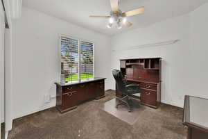 Office area featuring dark colored carpet and a ceiling fan