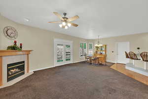 Living area featuring a tile fireplace, carpet, and a ceiling fan