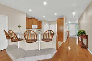Kitchen featuring light wood-type flooring, brown cabinets, recessed lighting, light countertops, and white microwave