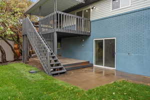 Exterior space with a patio area, brick siding, a lawn, stairway, and a wooden deck