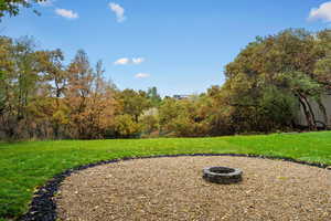 View of grassy yard with an outdoor fire pit
