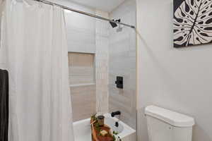 Bathroom with shower / bath combo with shower curtain and toilet