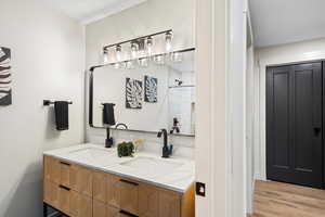 Bathroom featuring double vanity, a shower stall, and light wood-type flooring