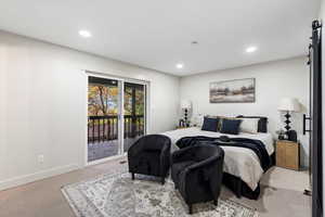 Primary Bedroom with a barn door, recessed lighting, and access to exterior