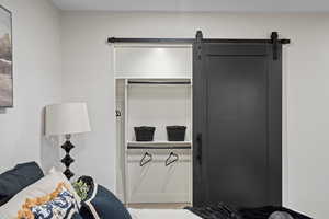 Bedroom featuring a barn door, wood finished floors, and a closet