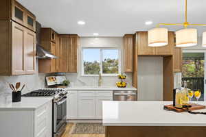 Kitchen featuring stainless steel appliances, pendant lighting, backsplash, wall chimney range hood, and recessed lighting