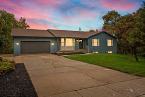 Rambler home featuring brick siding, concrete driveway, an attached garage, a front yard, and a shingled roof