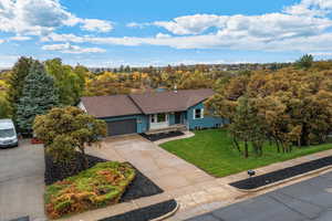 Rambler home with a front lawn, concrete driveway, a garage, a chimney, and covered porch