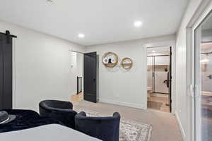 Bedroom with a barn door, carpet flooring, recessed lighting, and ensuite bathroom