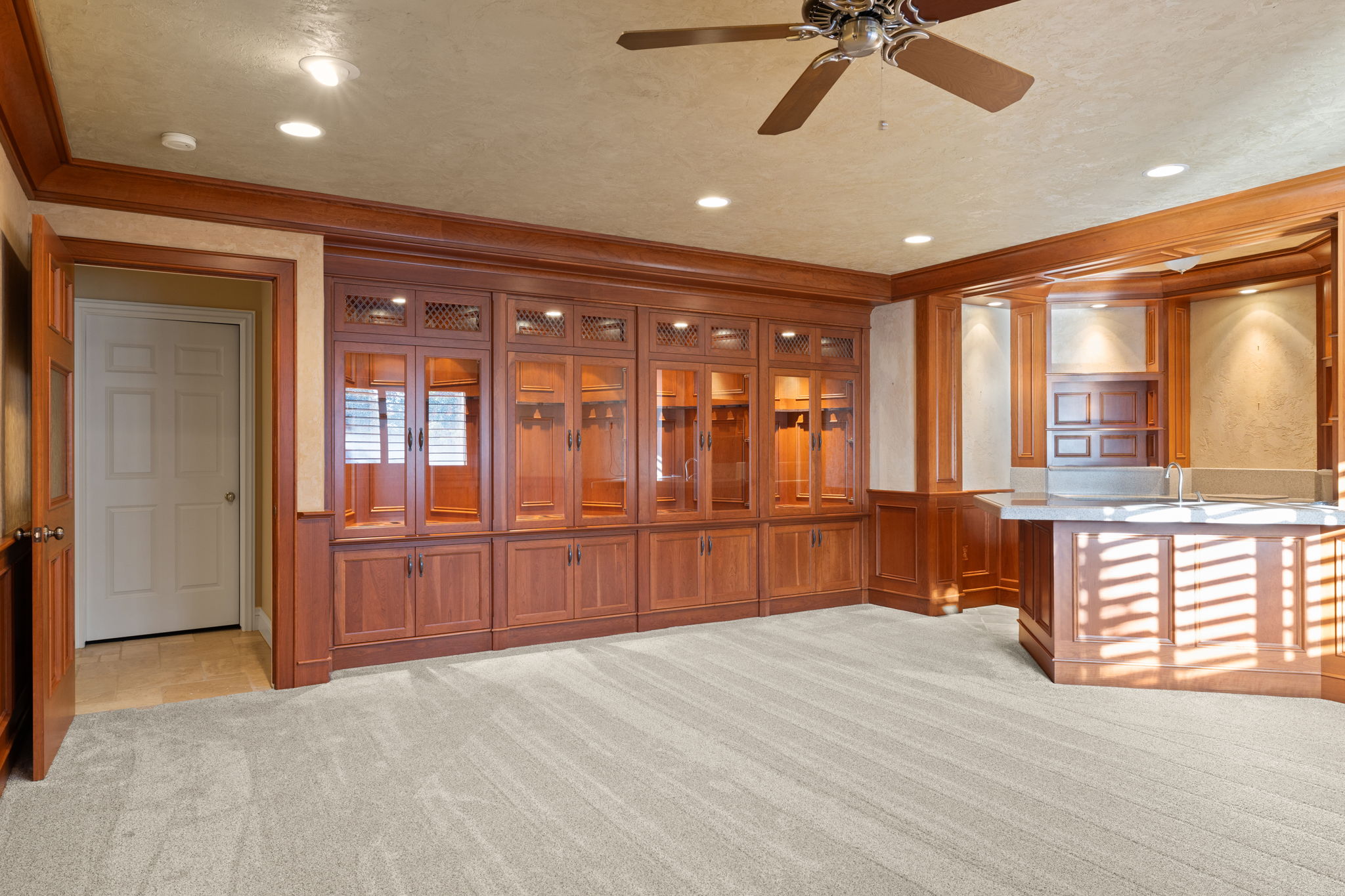 Den with cherry wood cabinets, custom gun display cabinet.