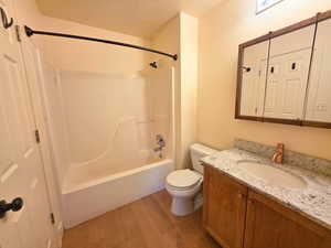 Full bathroom featuring light wood-type flooring, a textured ceiling, vanity, and shower / bathtub combination