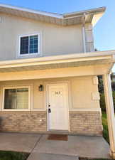 Entrance to property with covered porch, stucco siding, and brick siding