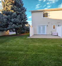 Back of property with a lawn, stucco siding, and a patio area
