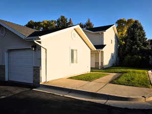 View of side of home with a lawn, stucco siding, and an attached garage