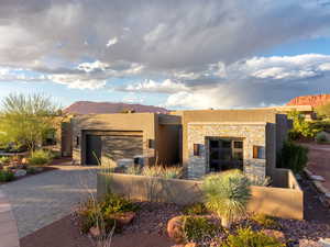 View of front of home with decorative driveway, stucco siding, a garage, and stone siding