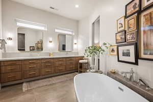Full bath featuring double vanity, a freestanding tub, tasteful backsplash, concrete flooring, and recessed lighting