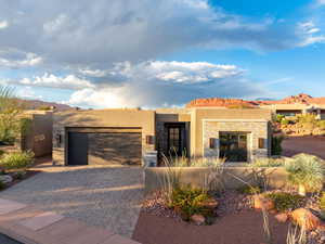 View of front of house featuring stucco siding, decorative driveway, stone siding, an attached garage, and a mountain view