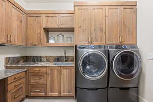 Washroom featuring cabinet space, washing machine and clothes dryer, and light tile patterned floors