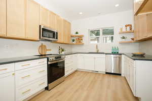 Kitchen featuring open shelves, stainless steel appliances, light wood-type flooring, light brown cabinetry, and recessed lighting