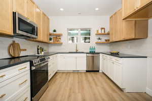Kitchen with open shelves, appliances with stainless steel finishes, backsplash, and recessed lighting