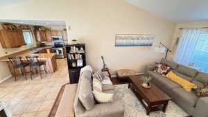 Living room with vaulted ceiling and light tile patterned flooring