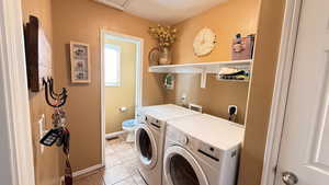 Washroom with light tile patterned floors and washer and clothes dryer