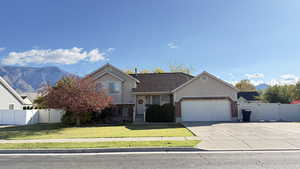 View of front of home featuring concrete driveway, stucco siding, a garage, brick siding, and a gate