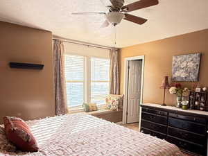 Carpeted bedroom with a textured ceiling and ceiling fan