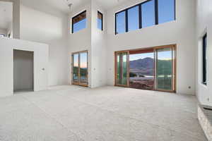 Unfurnished living room featuring plenty of natural light, a high ceiling, and carpet