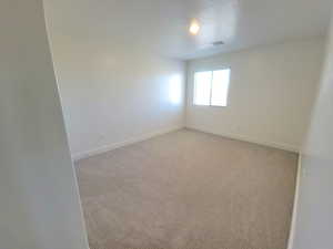 Spare room featuring light colored carpet and a textured ceiling