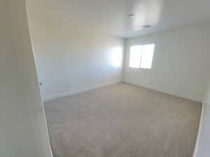 Spare room featuring light colored carpet and baseboards