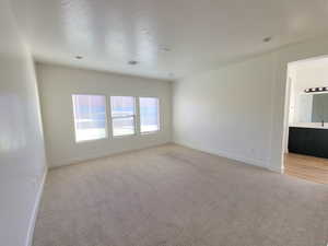 Empty room with light carpet and a textured ceiling