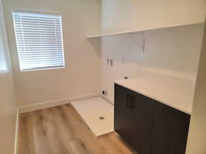 Washroom with hookup for a washing machine, light wood-style floors, and cabinet space