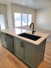 Kitchen with an island with sink, stainless steel dishwasher, gray cabinetry, light wood finished floors, and recessed lighting