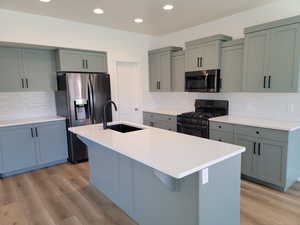 Kitchen featuring gray cabinets, appliances with stainless steel finishes, decorative backsplash, and recessed lighting