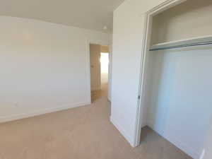 Unfurnished bedroom with light colored carpet and a closet