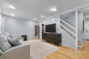 Living room with original hardwood flooring, recessed lighting, and blue pine stairway
