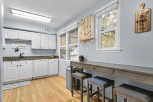 Kitchen with white cabinets, granite countertops, healthy amount of natural light, original hardwood flooring, and white dishwasher