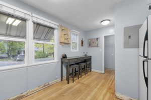 Kitchen with original hardwood flooring, freestanding refrigerator, and electric panel