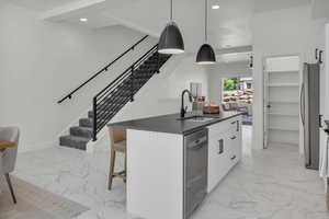 Kitchen featuring white cabinets, a kitchen island with sink, a breakfast bar, recessed lighting, and hanging light fixtures