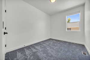 Unfurnished room with baseboards and dark colored carpet