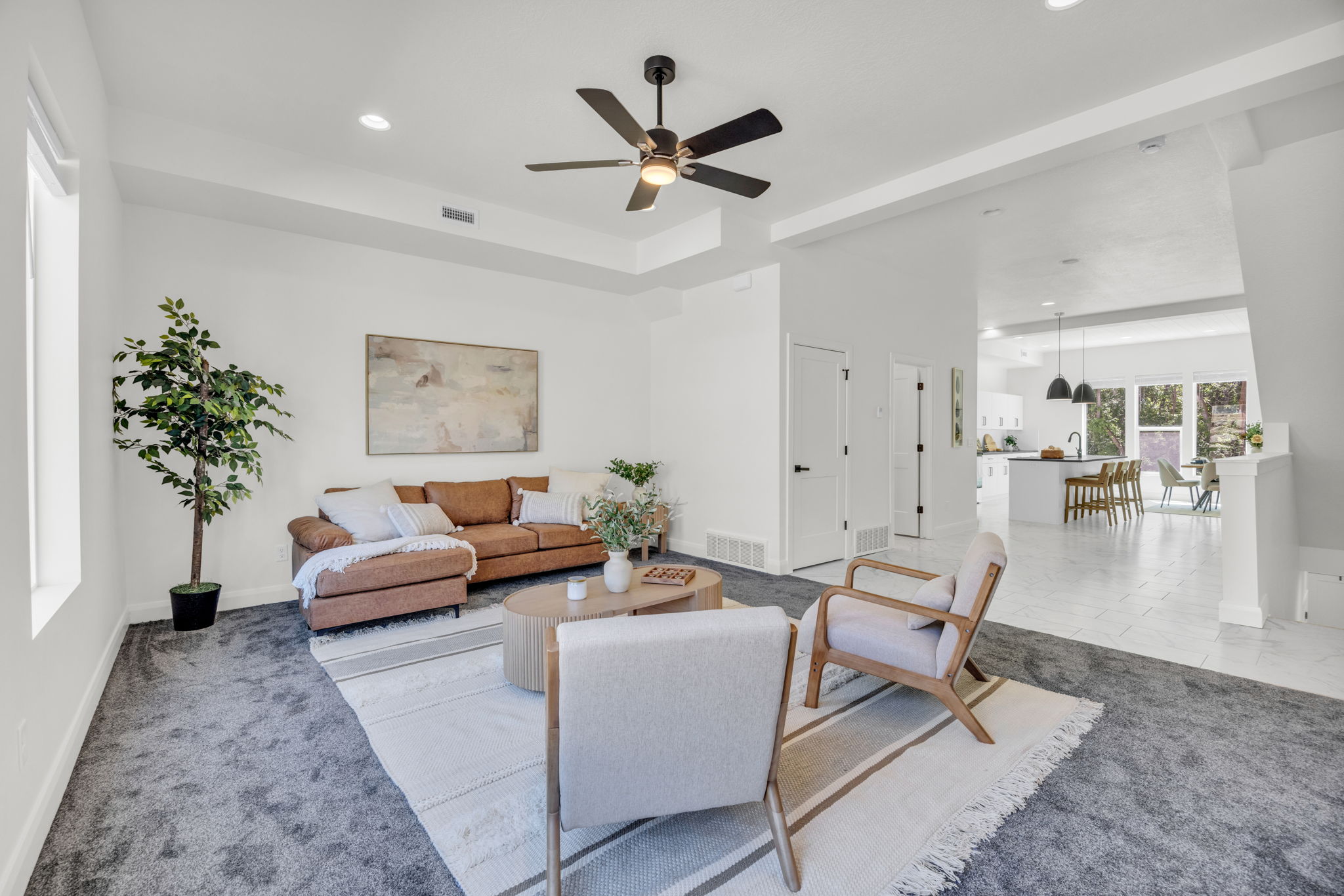 Carpeted living area with a ceiling fan, recessed lighting, and a tray ceiling