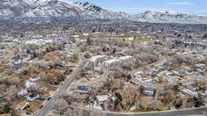 Aerial view of property and surrounding area featuring a mountainous background and nearby suburban area