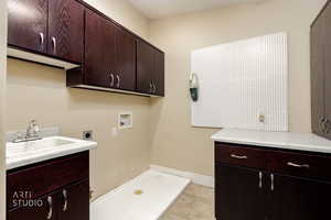 Washroom featuring cabinet space, hookup for a washing machine, hookup for an electric dryer, and light tile patterned floors