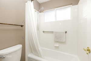 Bathroom featuring shower / bath combination with curtain and toilet