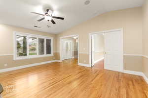 Empty room featuring light wood-style floors, vaulted ceiling, and a ceiling fan