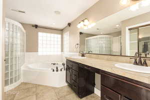 Bathroom with a bath, double vanity, light tile patterned flooring, and a stall shower