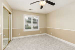 Unfurnished bedroom featuring a closet, light colored carpet, and ceiling fan